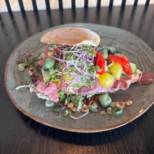 Pastrami, sla, kerrie-mayonaise, komkommer, tomaat, amsterdamse ui en wasabinootjes